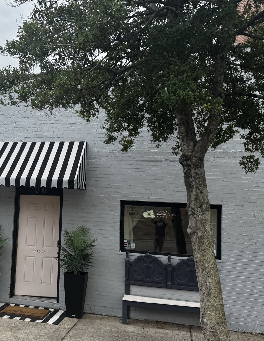 The Cabana entrance at 206 S Steele Street: a blush pink door under a black and white striped awning, with a bench beside the window